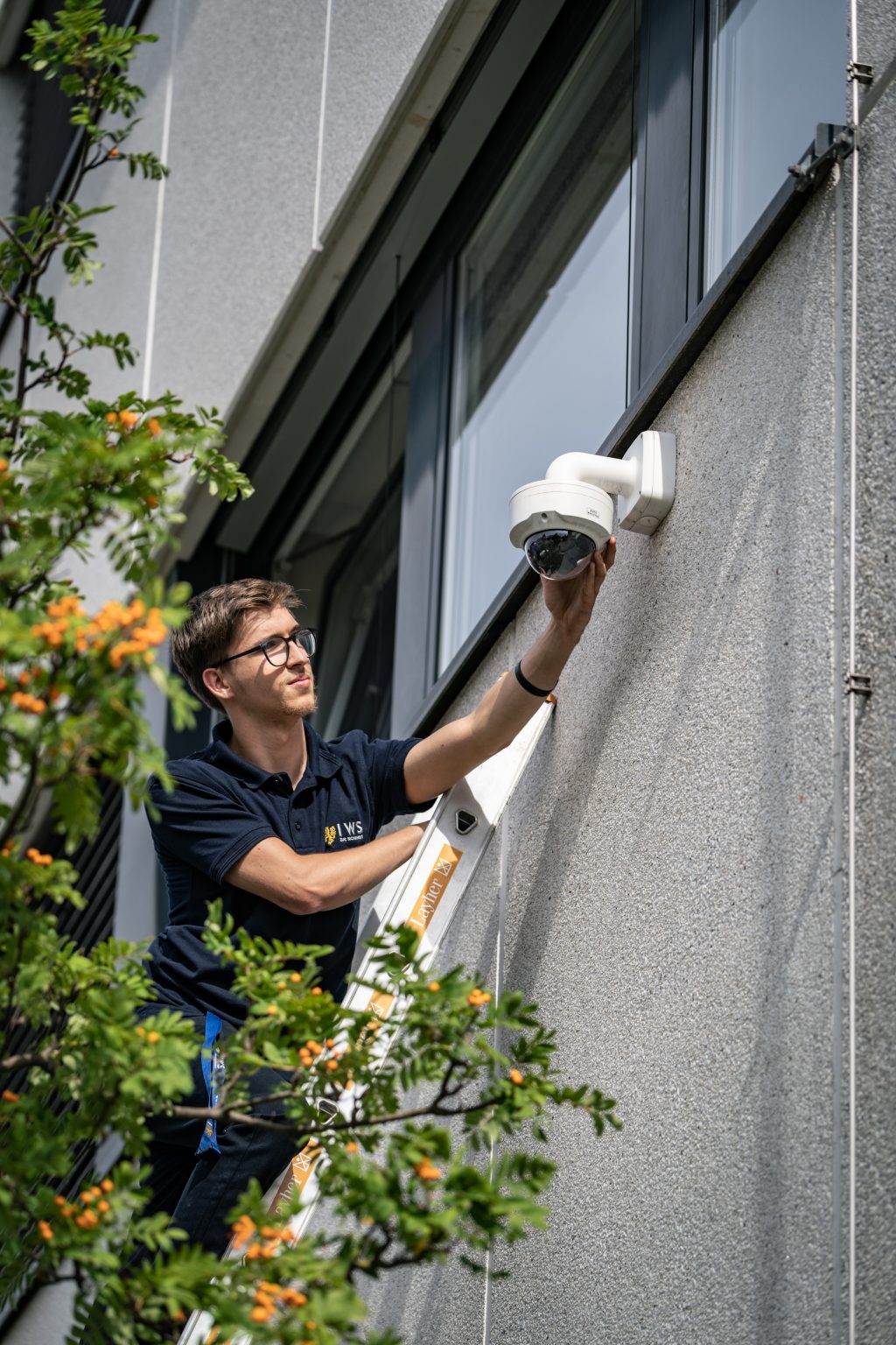 Techniker montiert eine Überwachungskamera an einer Fassade