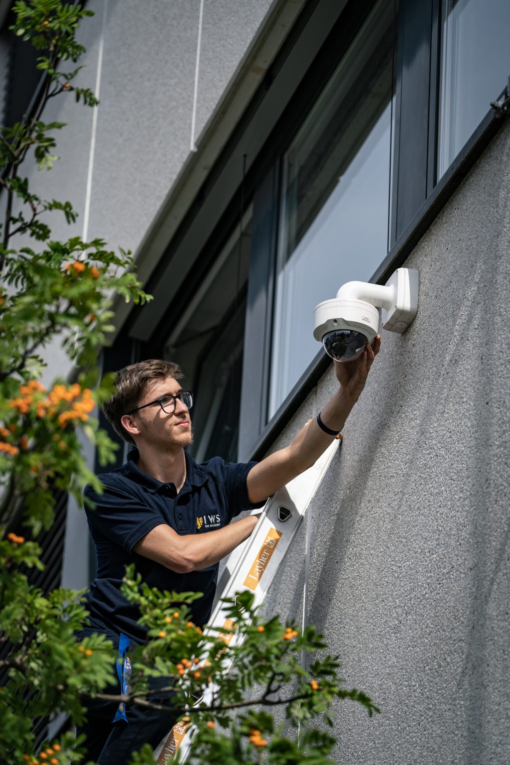 Techniker installiert eine Überwachungskamera an einer Gebäudefassade