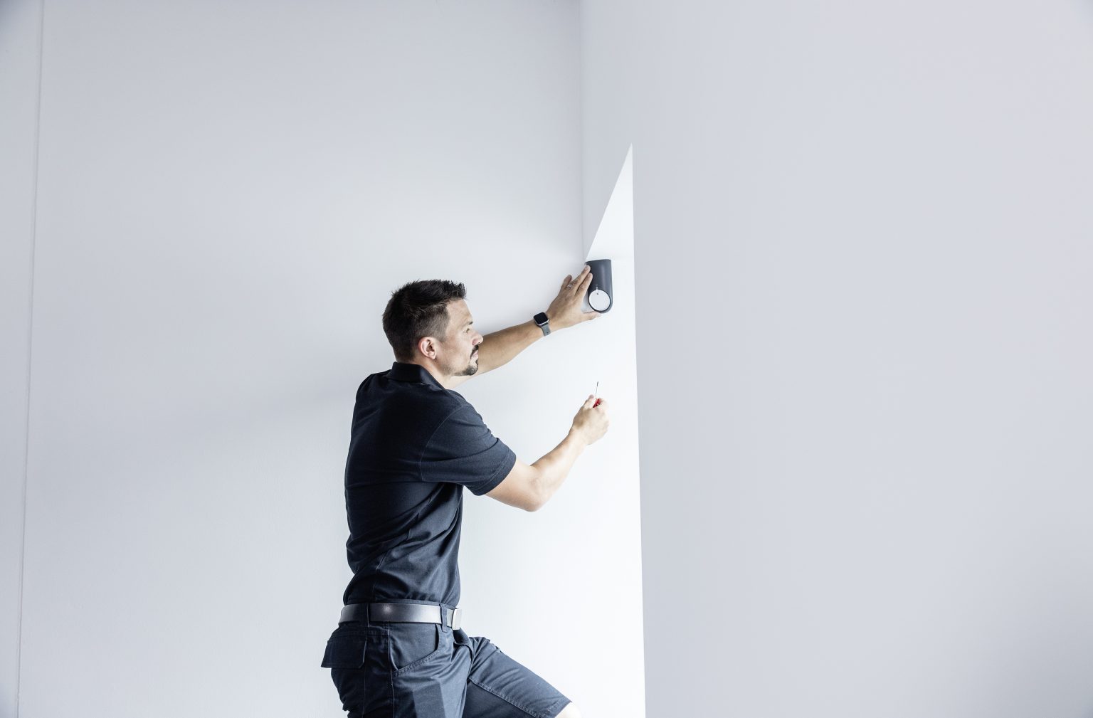 IWS-Techniker montiert ein Gerät an einer Wand