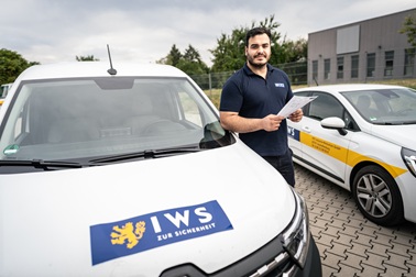 IWS-Mitarbeiter mit Einsatzunterlagen vor den Dienstfahrzeugen
